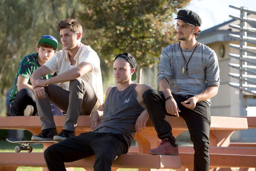 Cole and his friends sit side-by-side on a picnic table at a sunny Southern California park. They wear moody expressions, their gazes fixed beyond the frame.